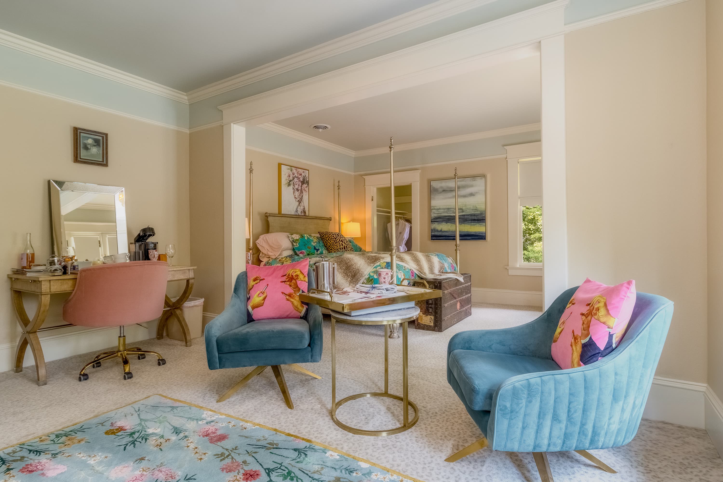 A spacious carpeted sitting area with matching blue armchairs, an occasional table, and a dressing table with chair & mirror.
