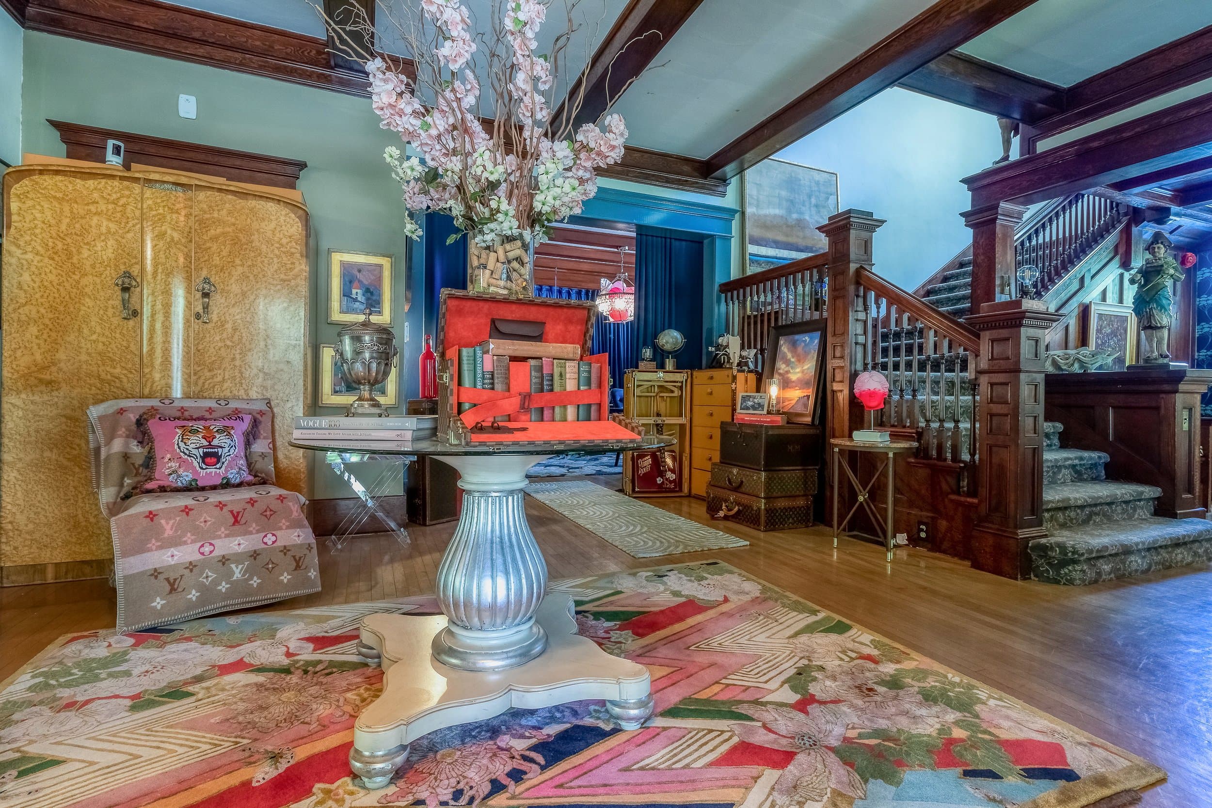 A stylish interior featuring a colorful rug, a vintage chair, and an array of decorative items and furniture.