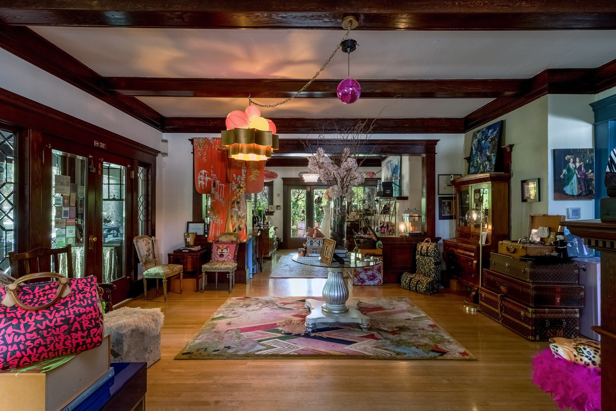 A vibrant, eclectic living room featuring wooden beams, colorful decor, and antique furnishings.