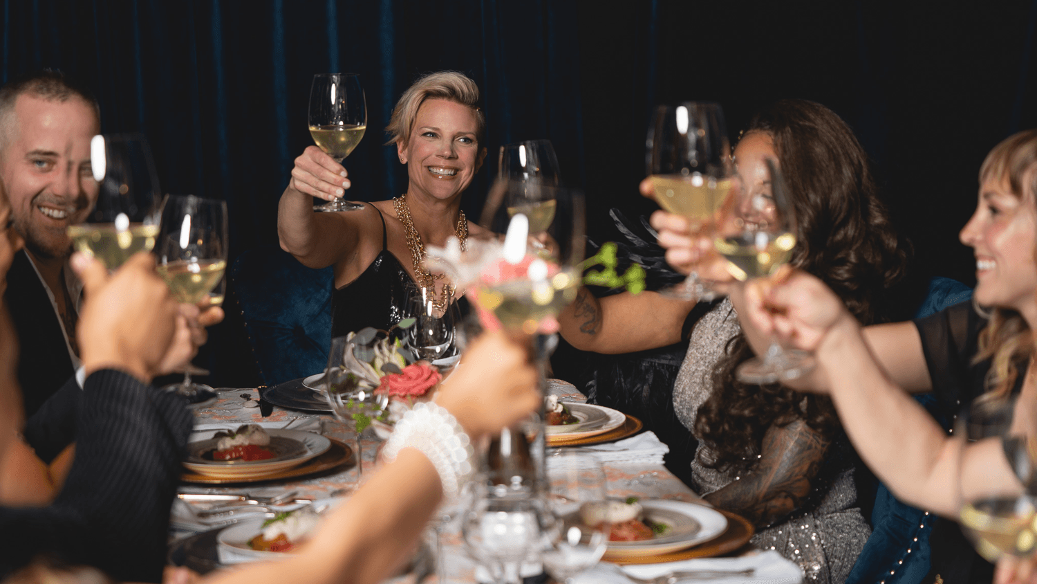 A group of friends toasting with glasses of champagne around an elegant dinner table.