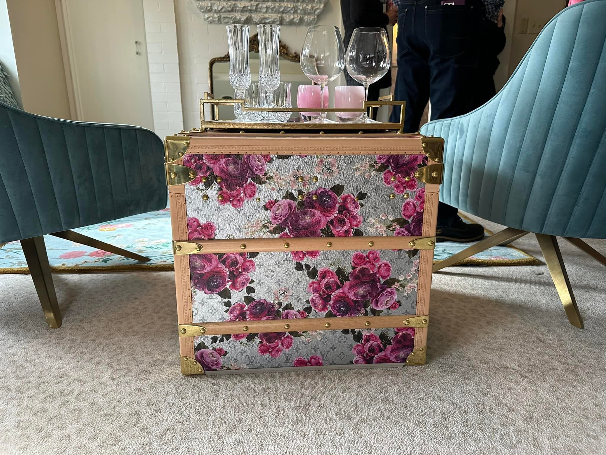 A decorative trunk with floral patterns serves as a coffee table, surrounded by stylish chairs.