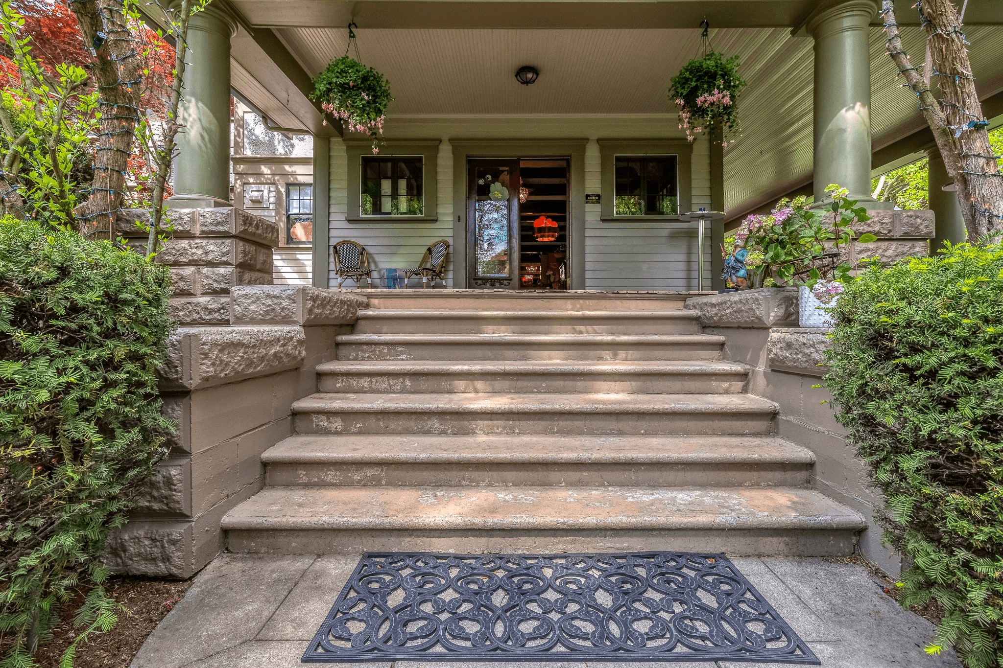 A set of stone steps leading to a charming porch adorned with plants and decorative elements.