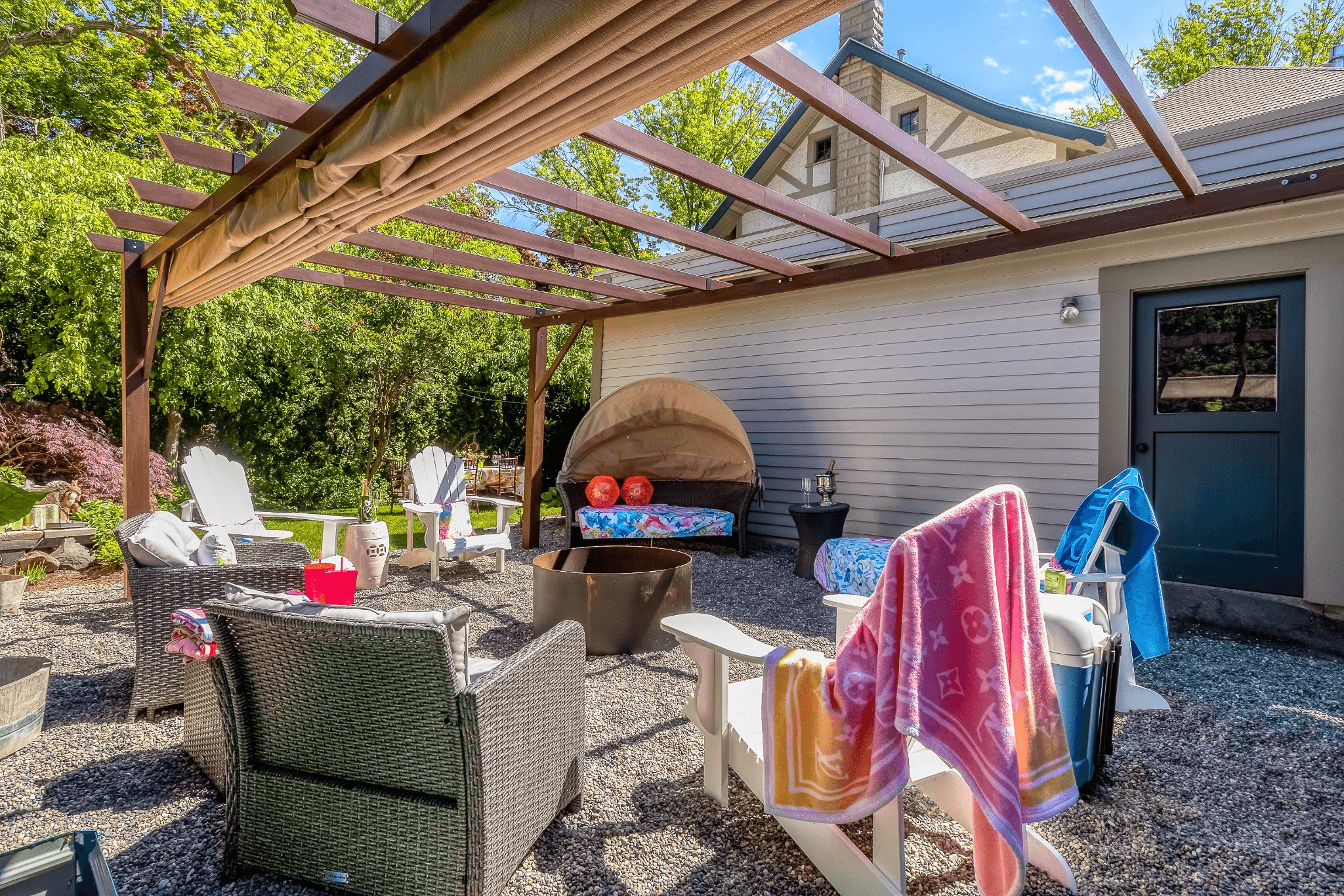 Wooden pergola over patio chairs set into a circle around a firepit