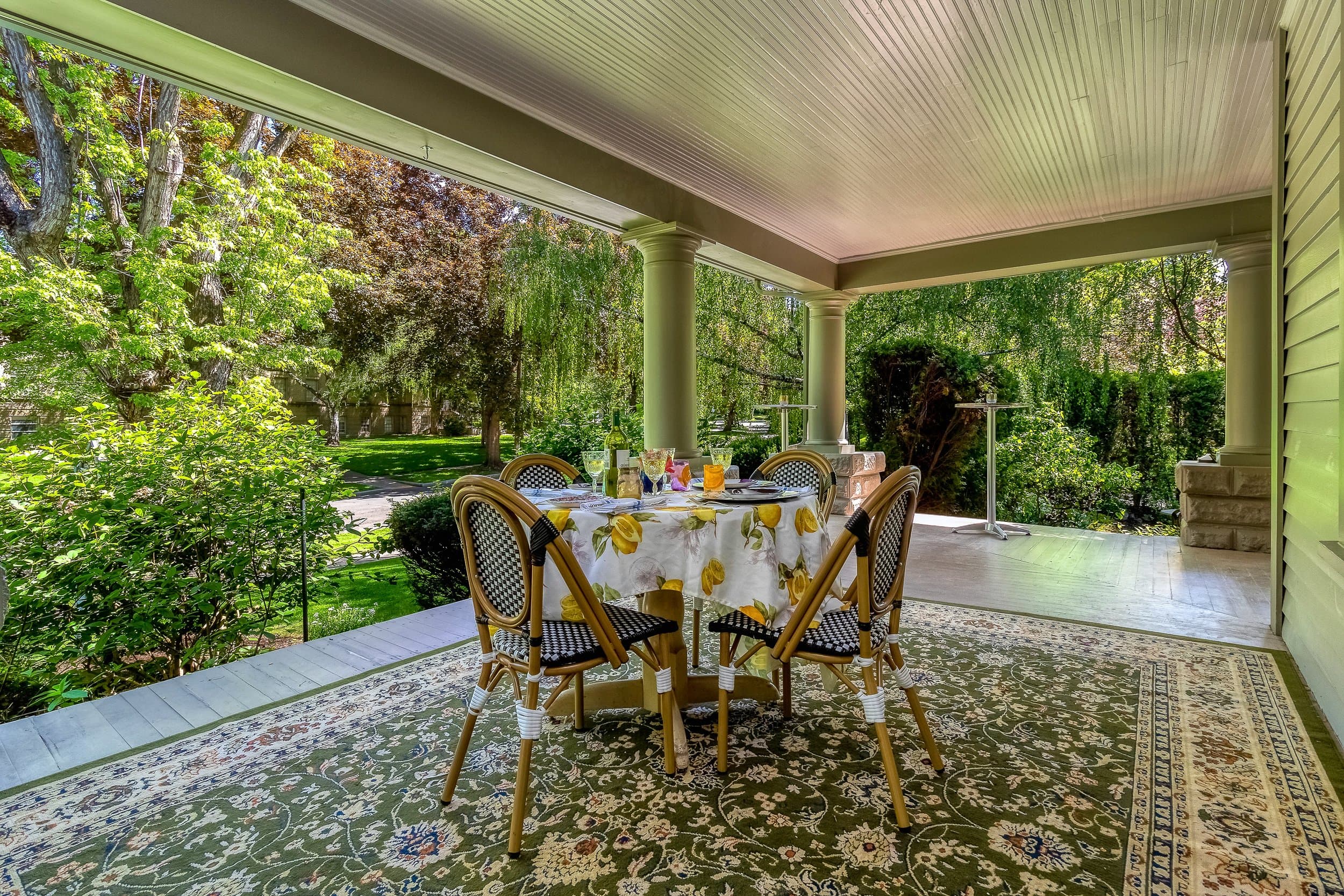 A table set with drinks and surrounded by greenery on a porch.