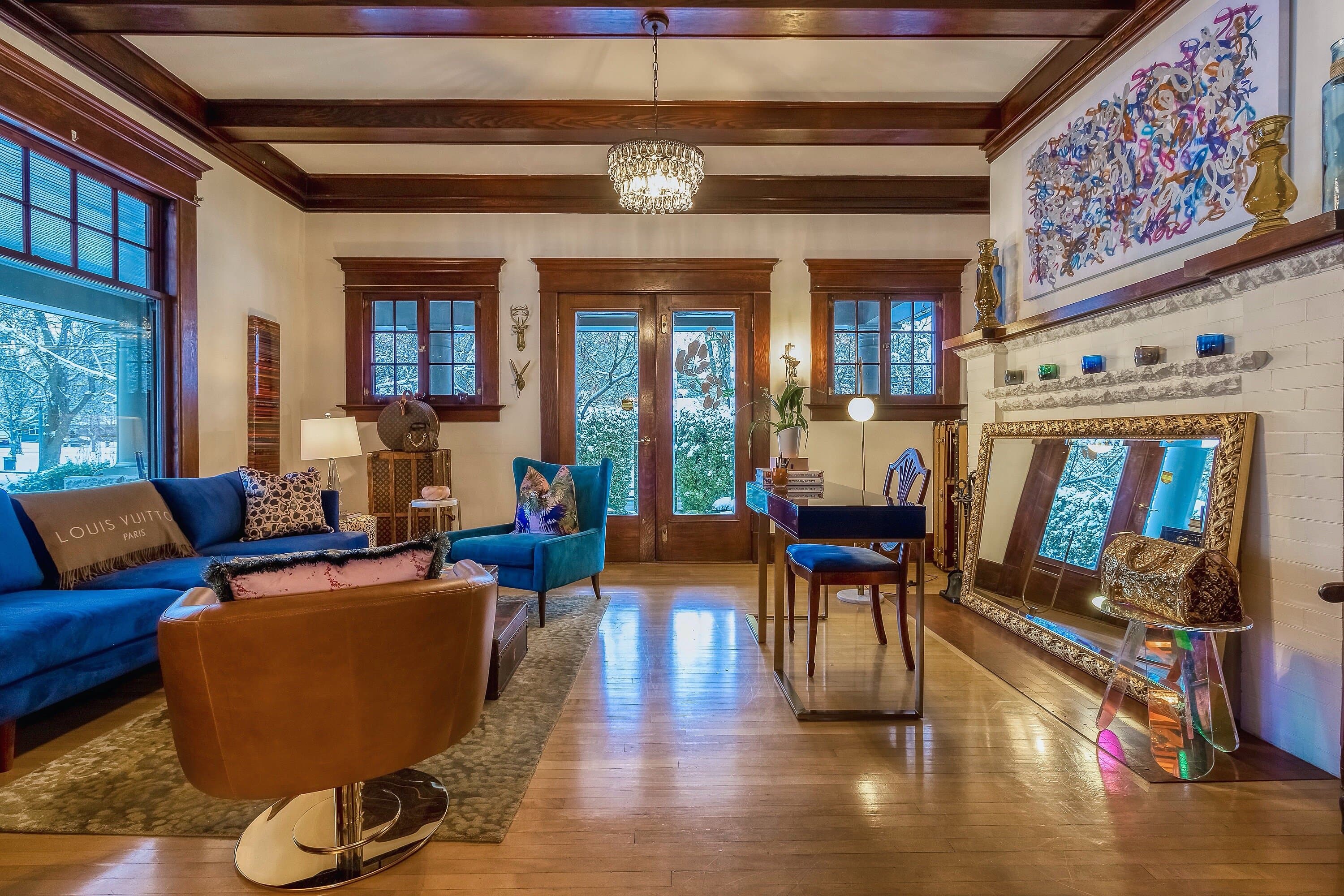 A stylish living room featuring blue sofas, hardwood floors, and elegant decor.